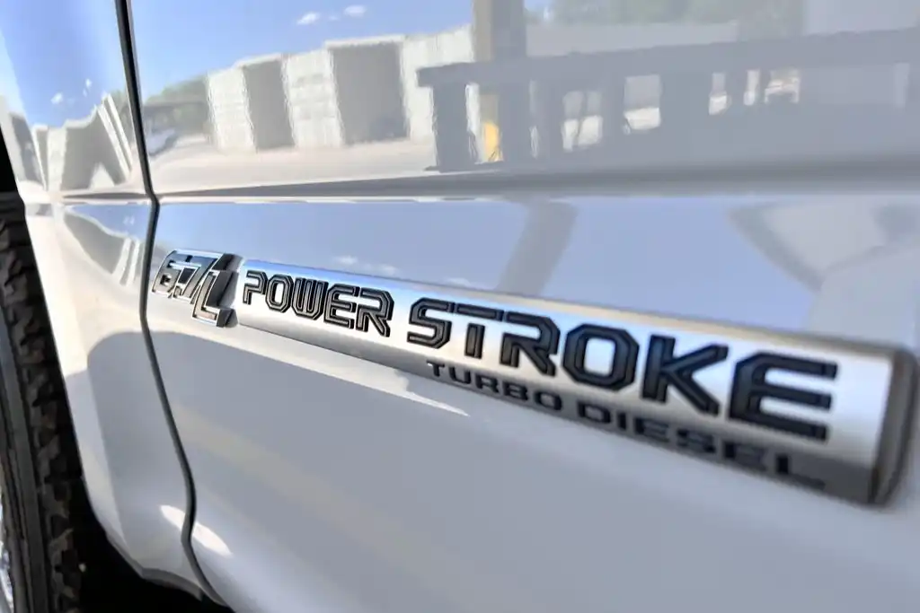Close-up of the 6.7L Power Stroke Turbo Diesel badge on the fender of a white heavy-duty pickup truck