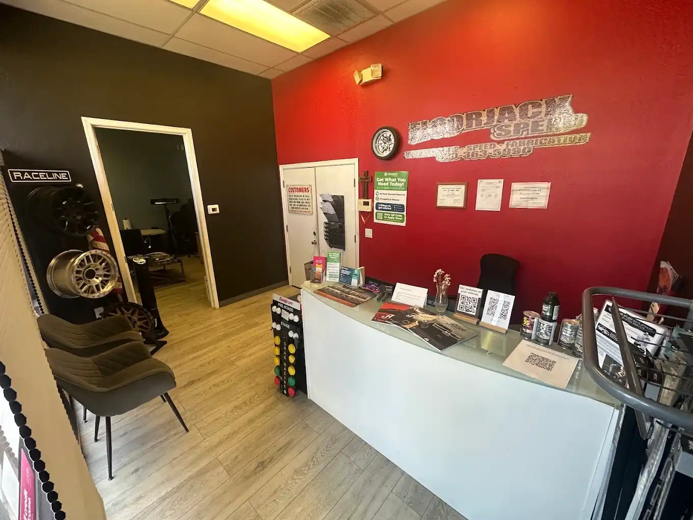 Inside the Floorjack Auto Repair front office in Phoenix — the customer counter beneath the red Floorjack Speed wall sign, with a wheel display and waiting-area seating