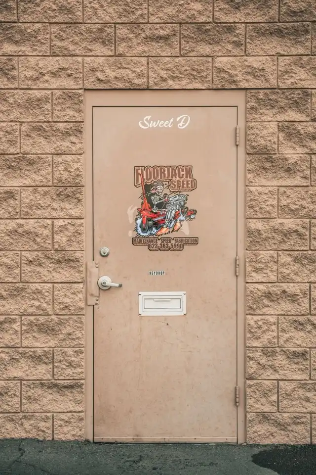 The Sweet D service door at Floorjack Auto Repair straight on, showing the Floorjack Speed decal and, below it, the mail slot labelled KEYDROP